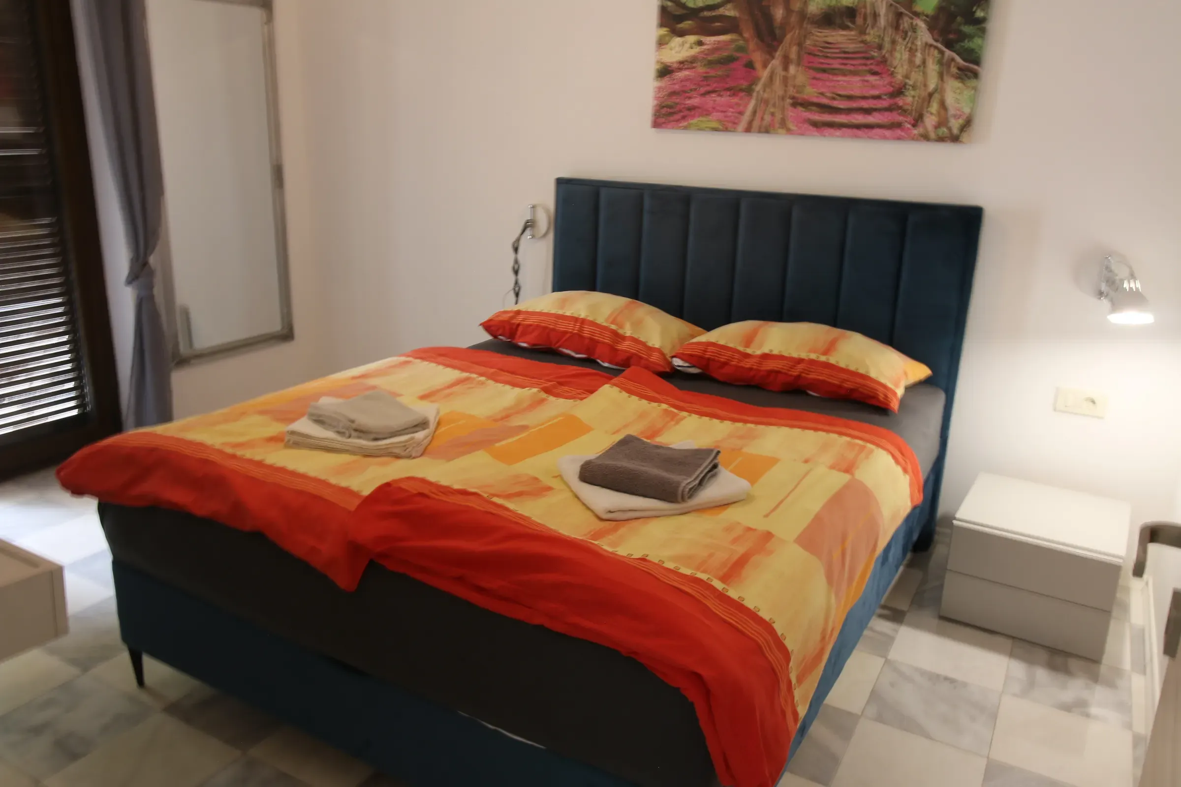 Double bedroom with a navy headboard and warm orange bedding