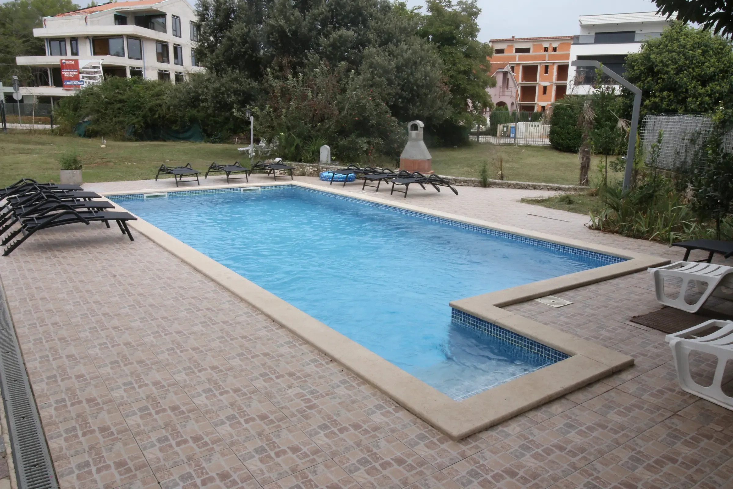 View across the pool and sun deck of the fenced villa estate