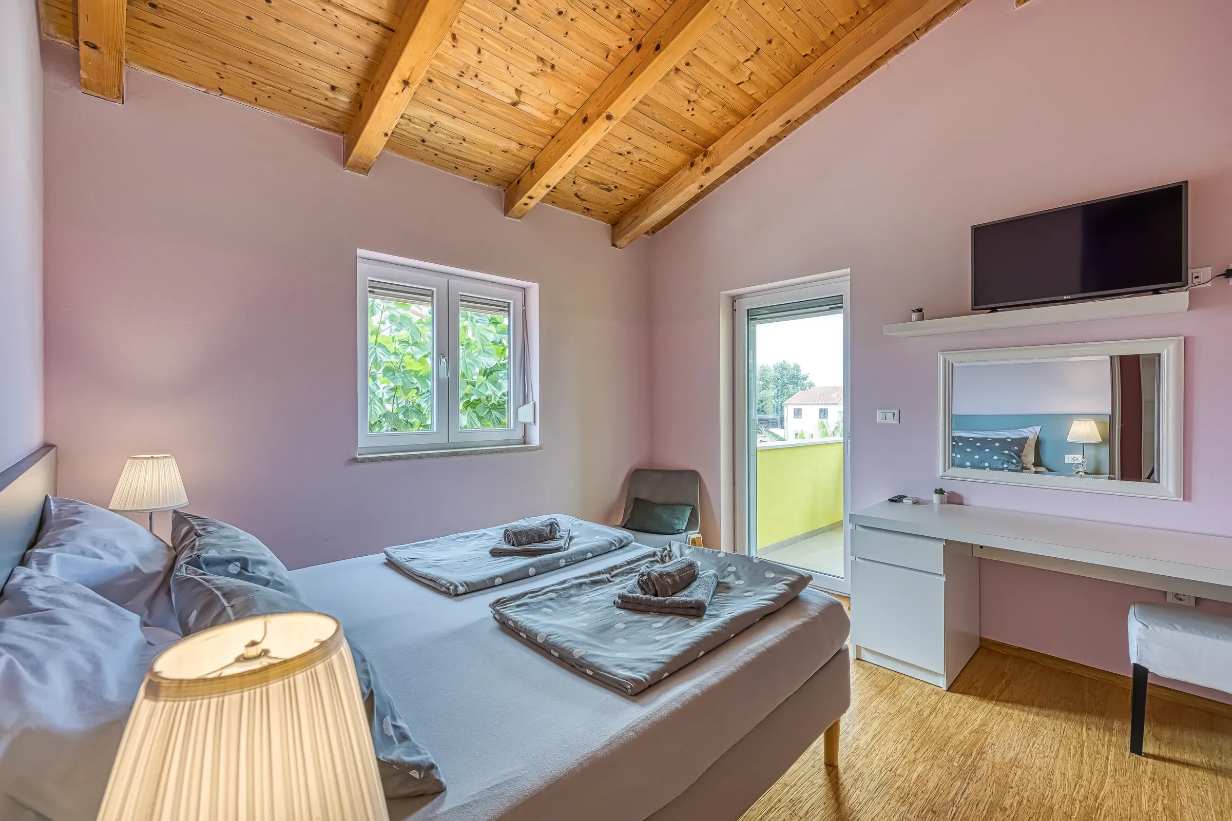 Soft pink attic bedroom with a desk and TV