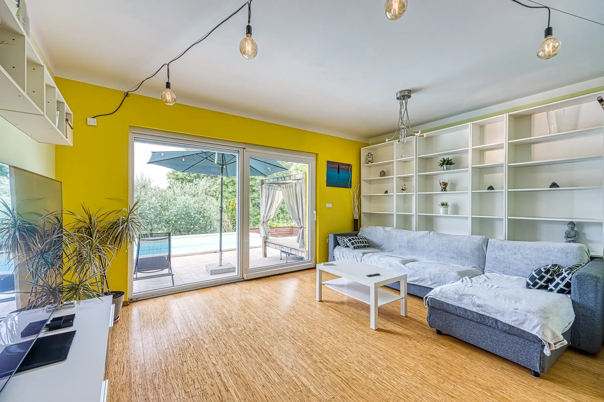 Bright living room with a corner sofa and doors to the pool terrace