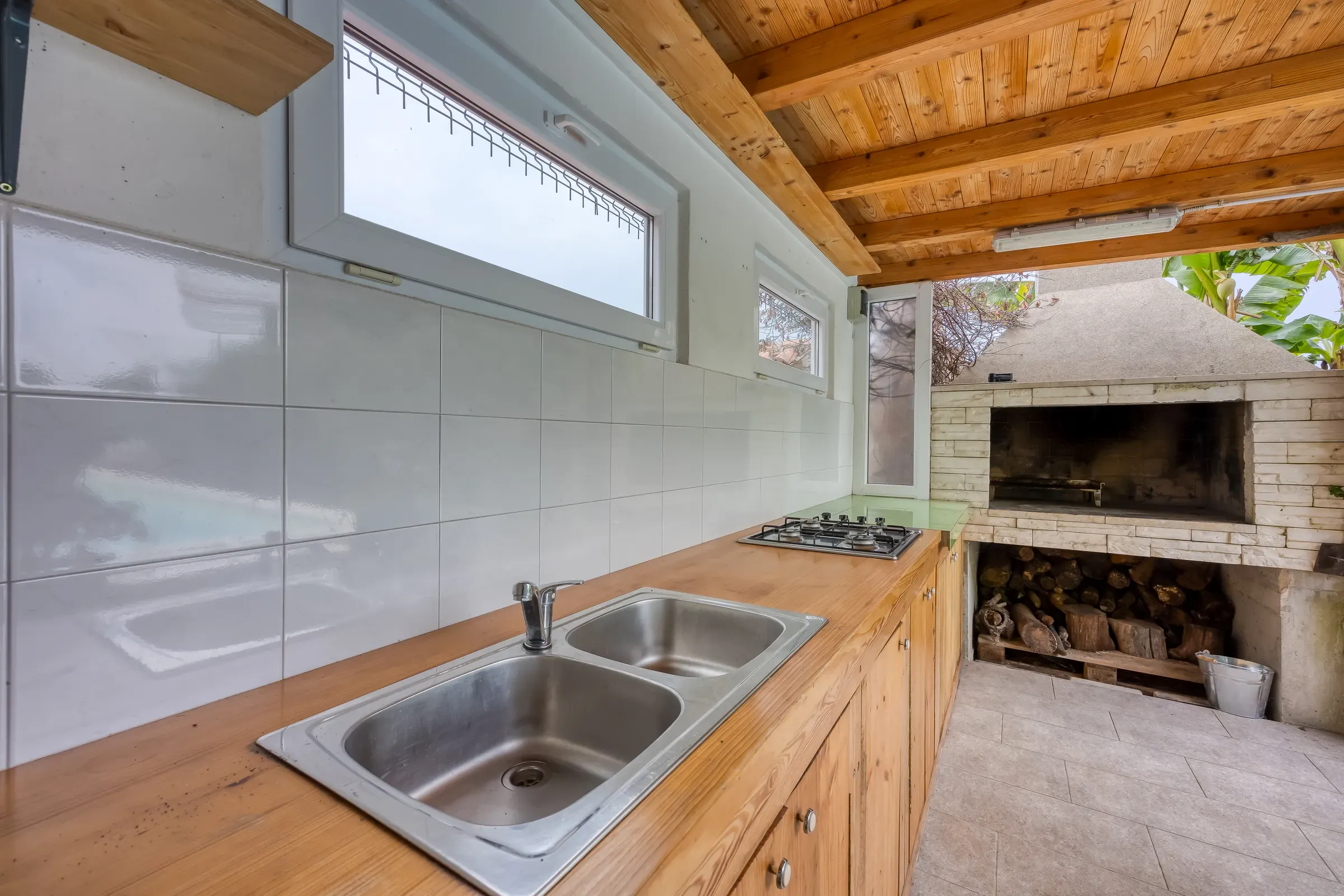 Fully equipped outdoor kitchen with sink, hob and open fireplace grill